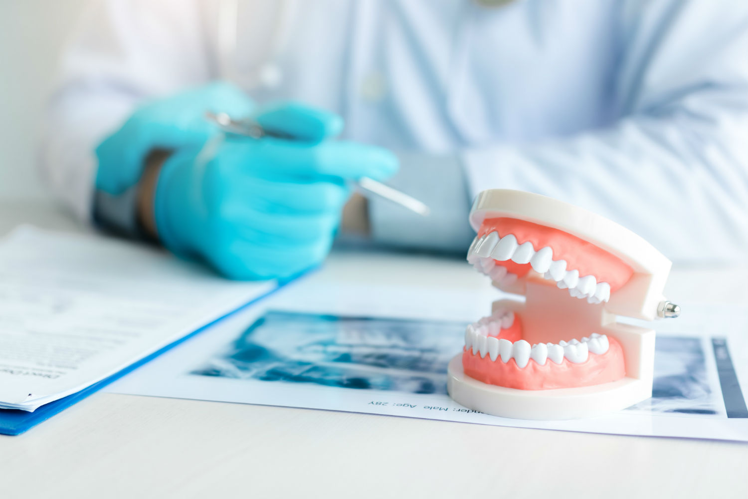 Stock image of dentures on table along with a faded image of a doctor