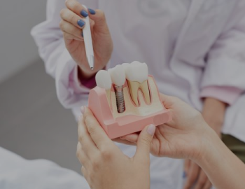 Closeup of unrecognizable female doctor pointing at tooth model while consulting patient