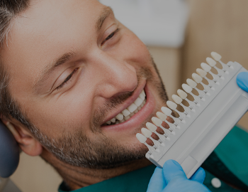 Dentist uses a palette tooth color sample to determine shade of patient's male teeth