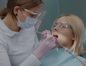 Young woman wearing protective glasses while dentist examining her teeth