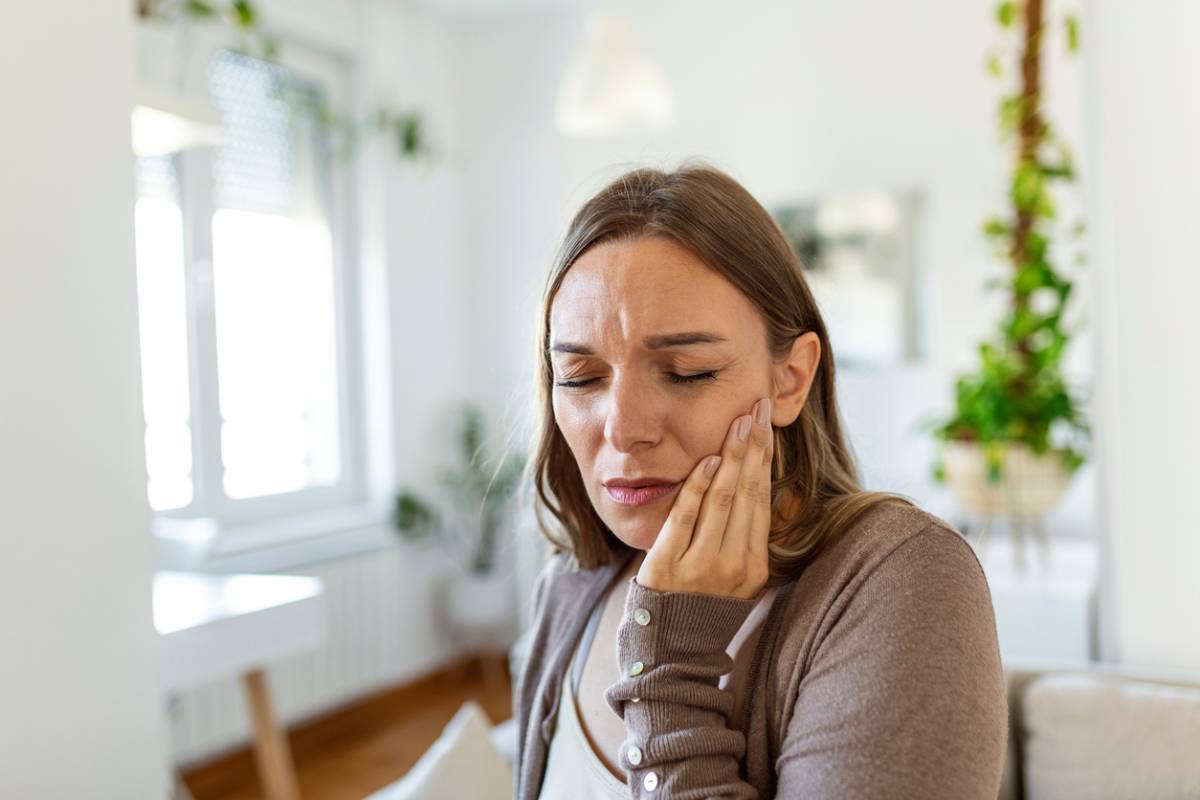 Woman with toothache, holding her jaw due to pain.